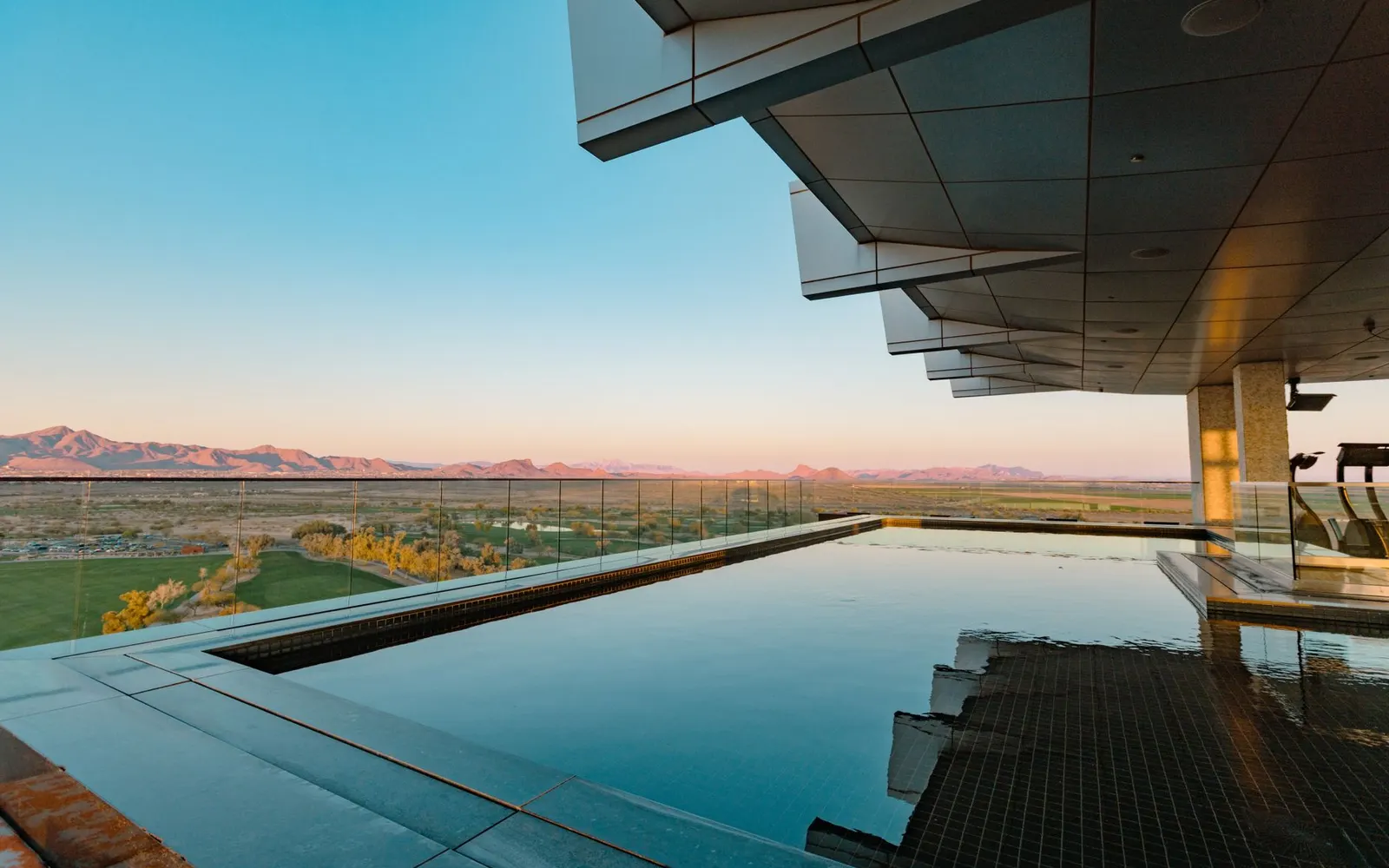 A finished pool deck and desert landscaping in the warm evening light typical of a Scottsdale-area backyard build